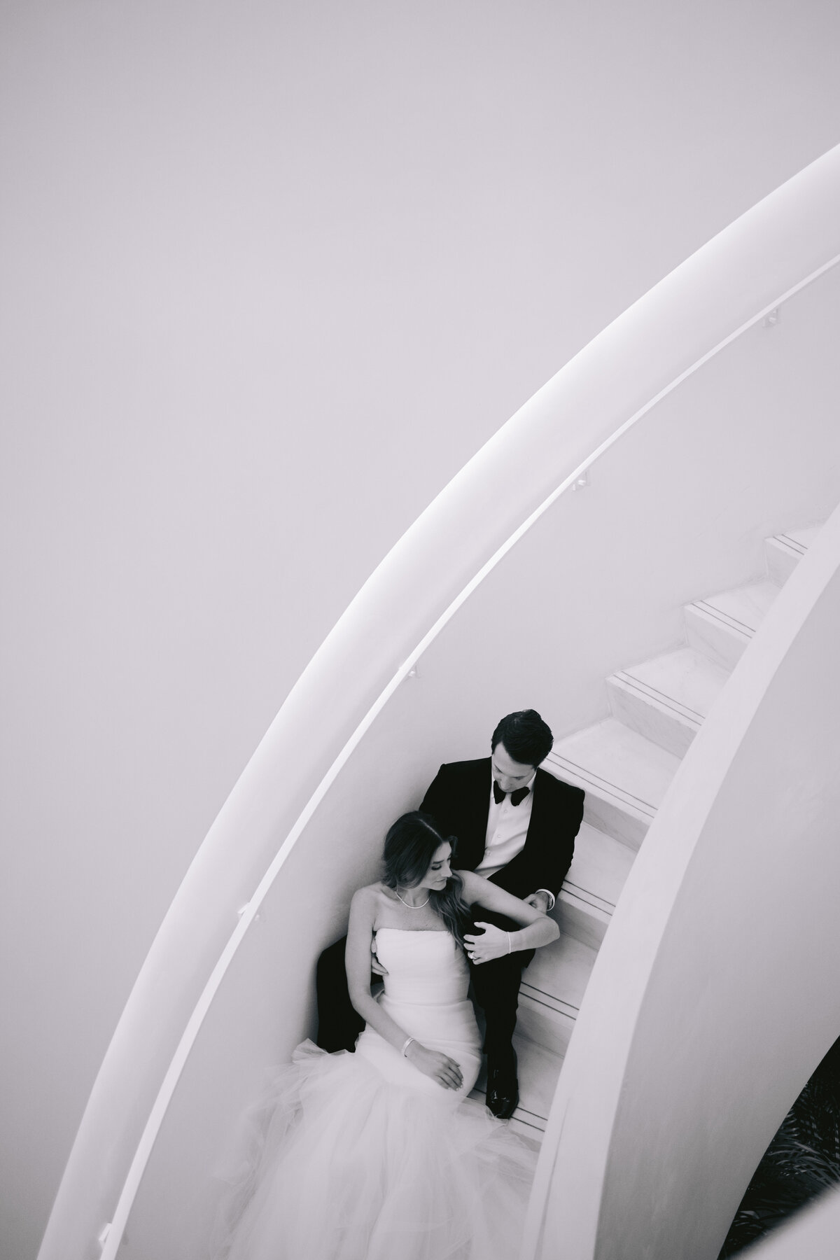 Bride and groom sitting closely on a curved staircase, captured by Rodrigo Varela Photography.