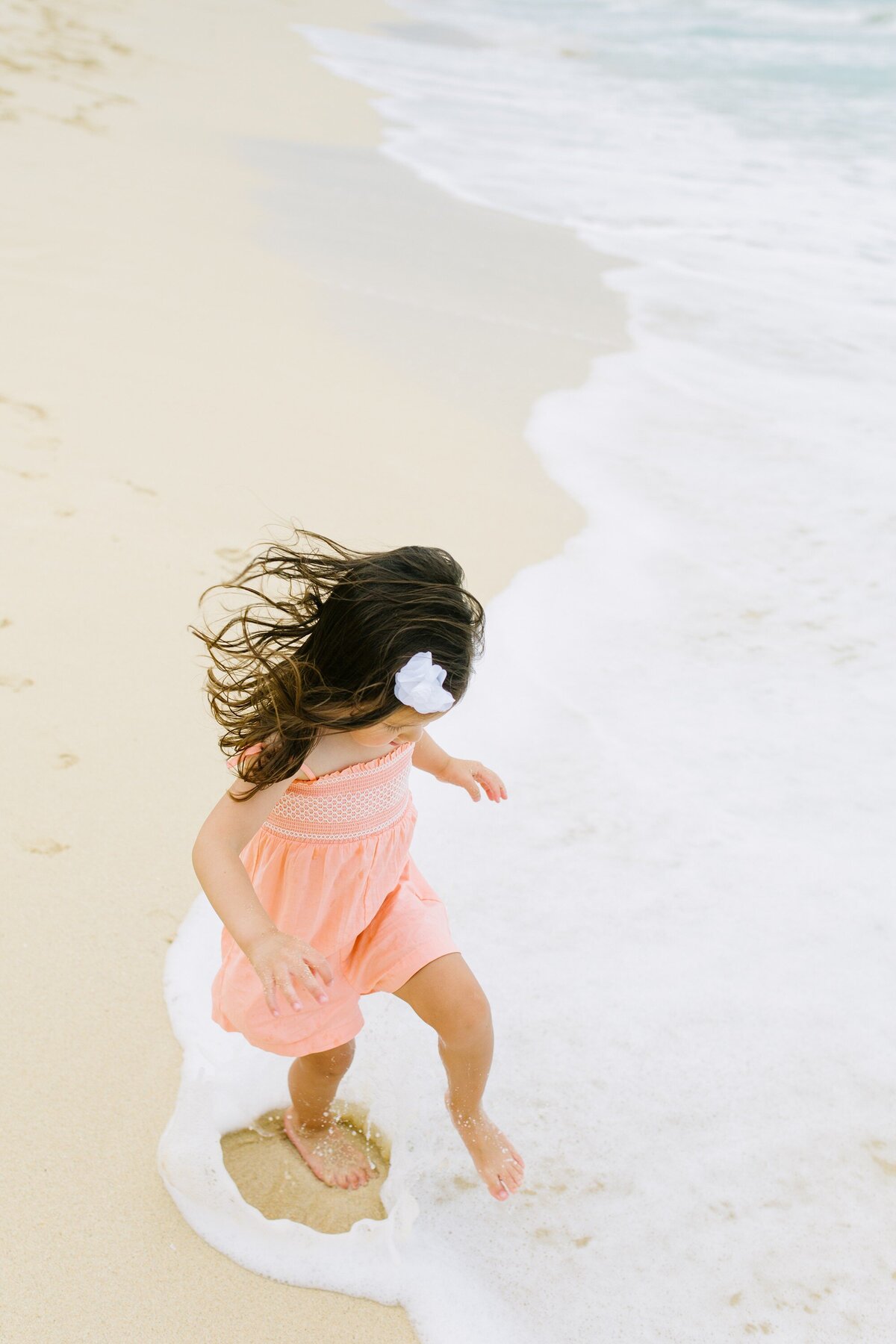 girl stomps in the foamy waves at waimanalo beach