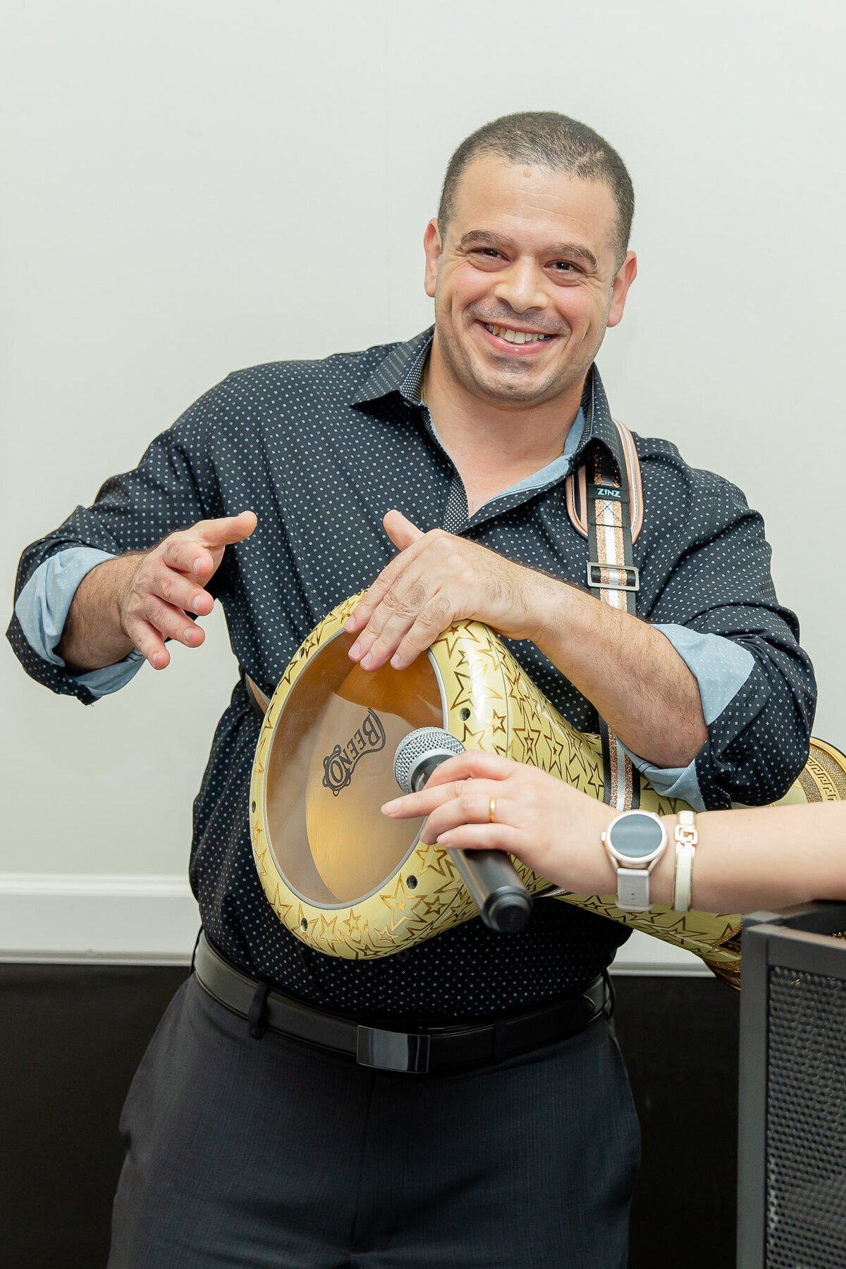 A man smiles as he demonstrates how to play a unique looking drum at an event.