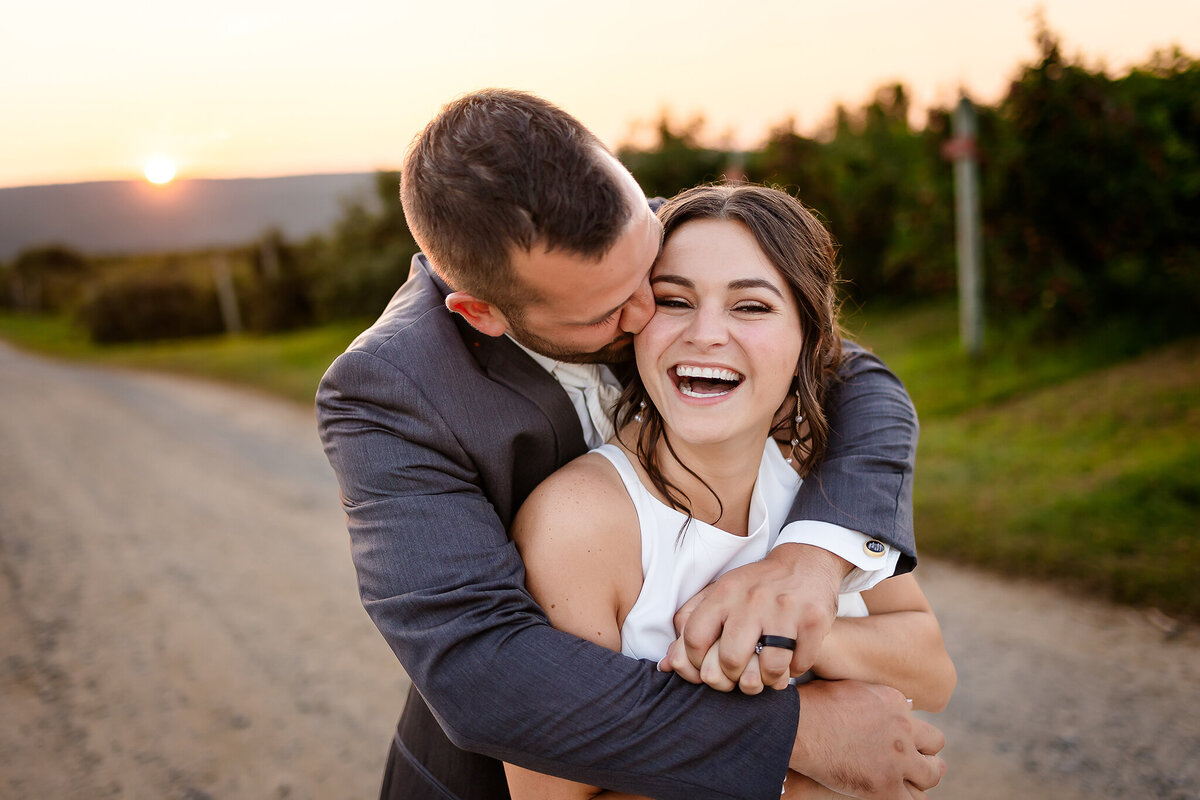 Groom bear hugging bride as she laughs joyfully in country wedding in NH