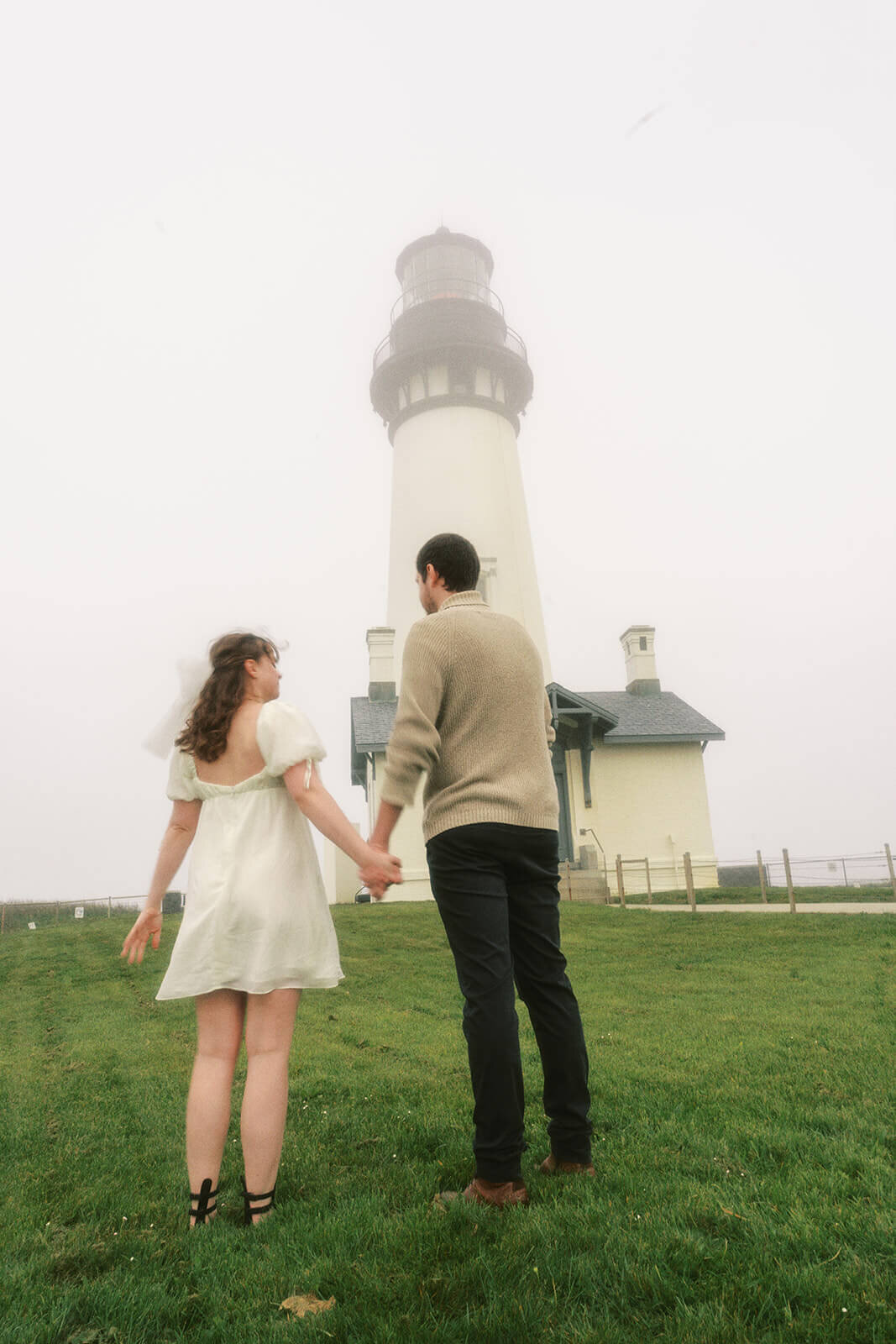 A couple holding hands at Yaquina Head Lighthouse. 