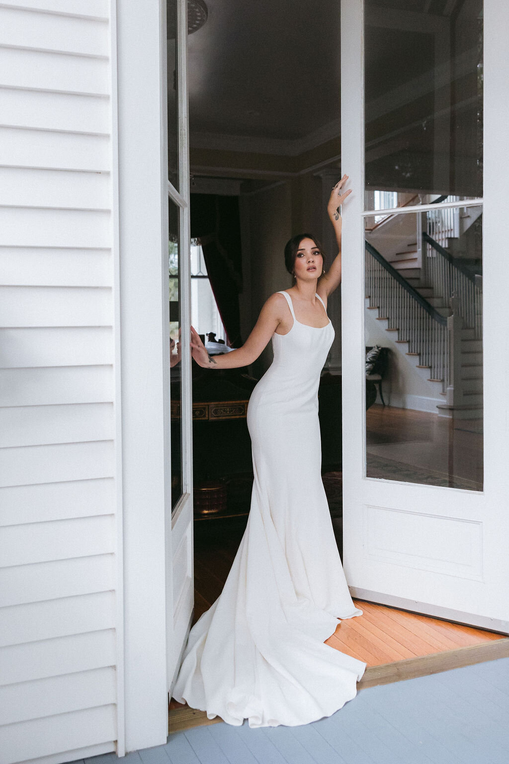 A stunning bride in a sleek white gown poses in a historic Charleston, SC wedding venue, exuding modern elegance and sophistication. Captured by Amia Marcell destination wedding photographer.