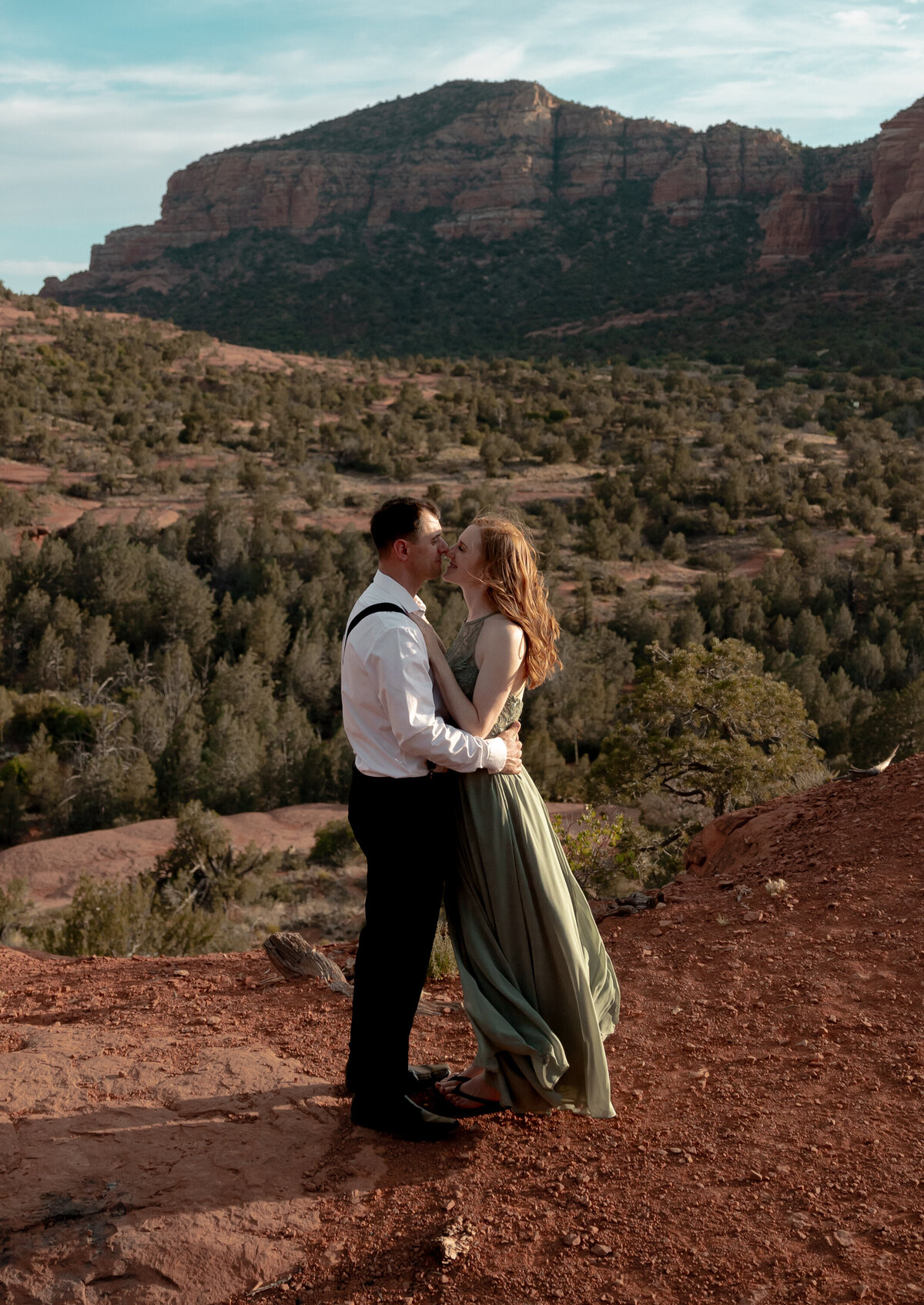 Couple standing against red rock backdrop during Sedona engagement session