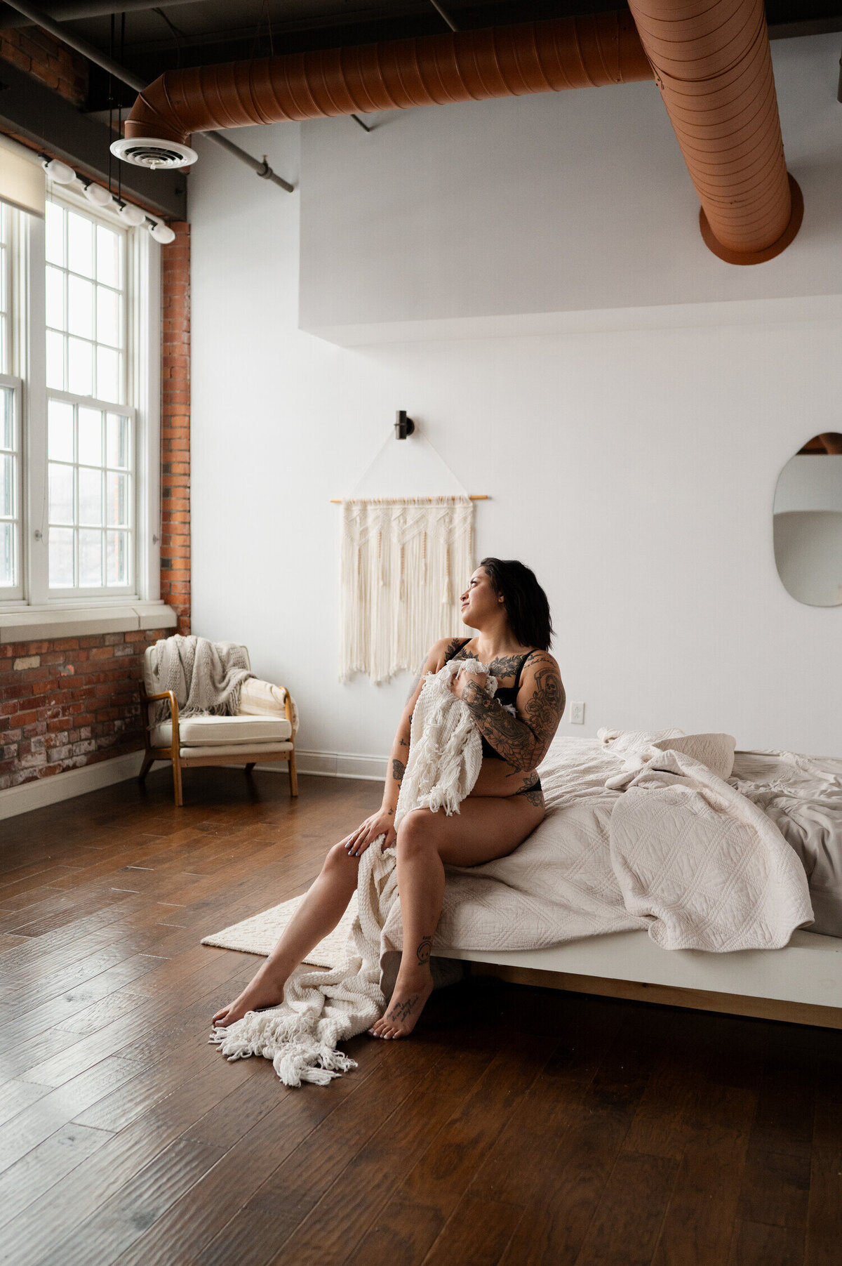 Covering up with a bed sheet during a boudoir photoshoot at a studio in Buffalo, New York.