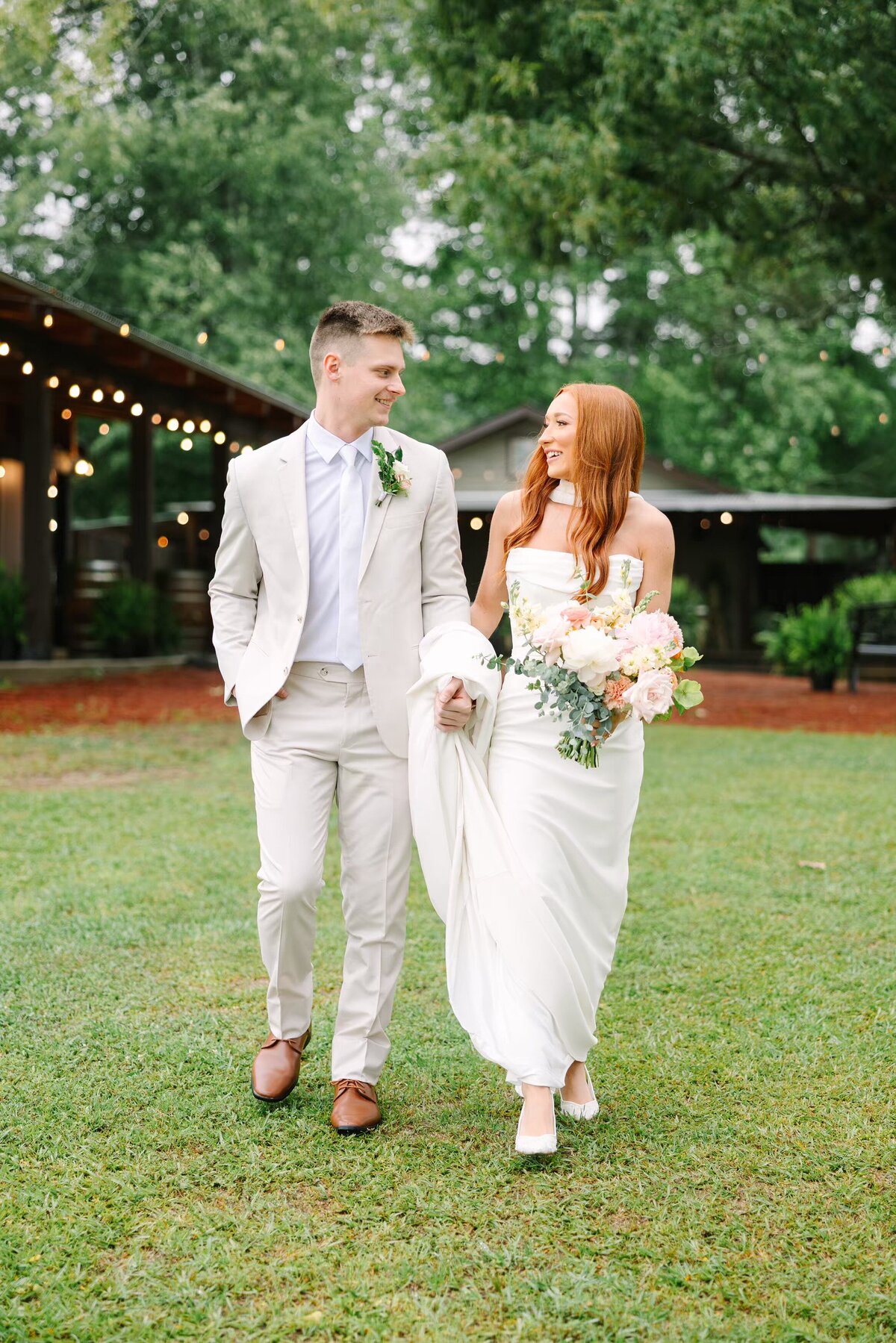Groom helps bride walk and carry dress on a rainy wedding day