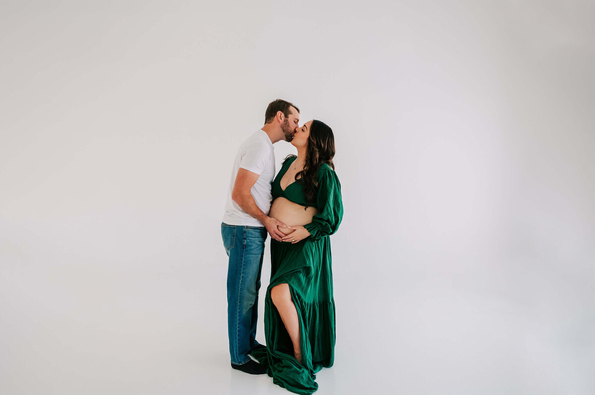 pregnant couple kissing in maternity photography studio in Branson
