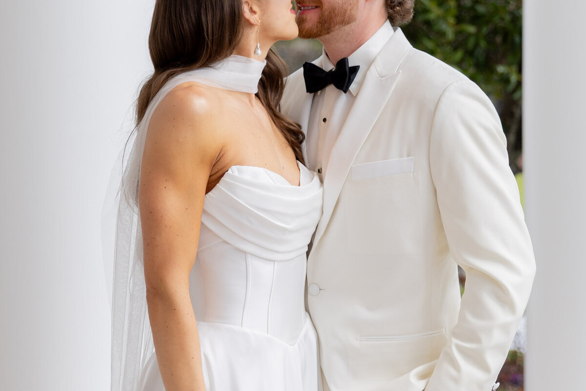 A bride and groom are about to kiss for a portrait on their wedding day. The photo is cropped so you can't see above their mouths.