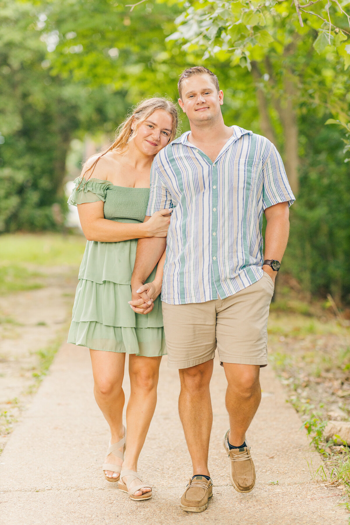 couple walking down sidewalk  together holding hands smiling