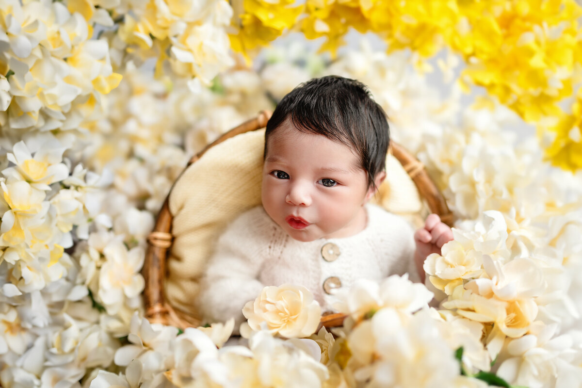 Newborn portrait captured in studio surrounded by soft yellow and ivory florals. A joyful and vibrant floral baby photo from Meraki Photographic Creations in Paris, Ontario.