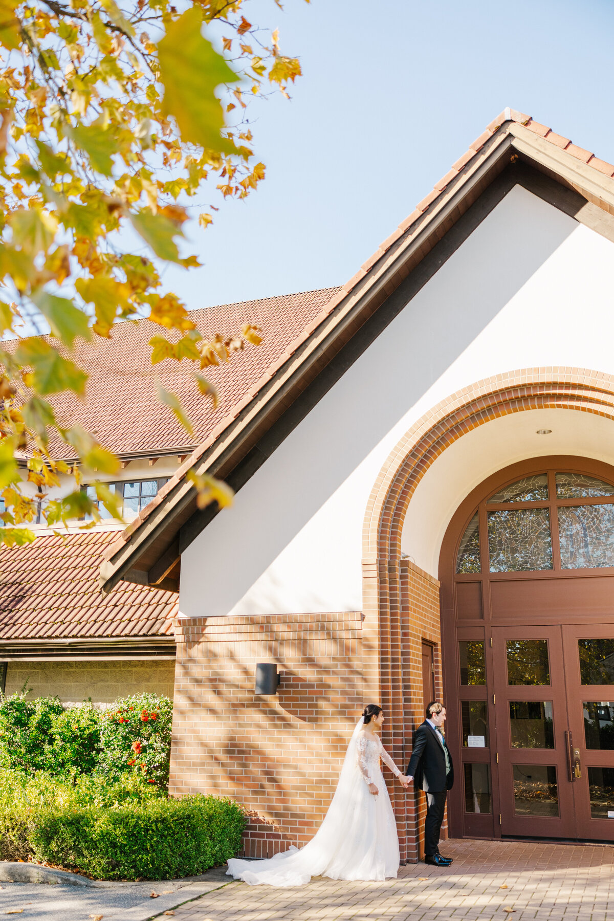 Bride and groom holding hands outside of the church building