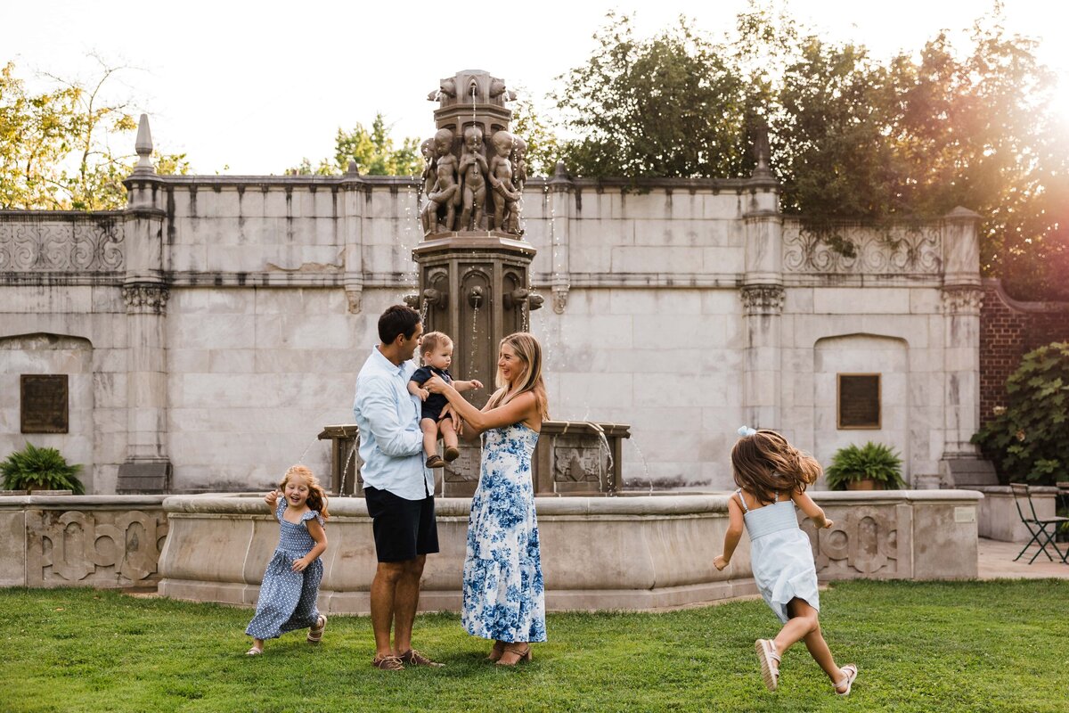 Family enjoying playtime near an ornate fountain in a park setting, captured by a skilled Pittsburgh family photographer.