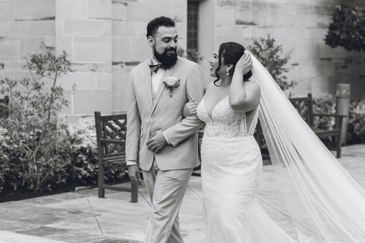 Bride and groom with looped arms walking in courtyard outside Houston TX church
