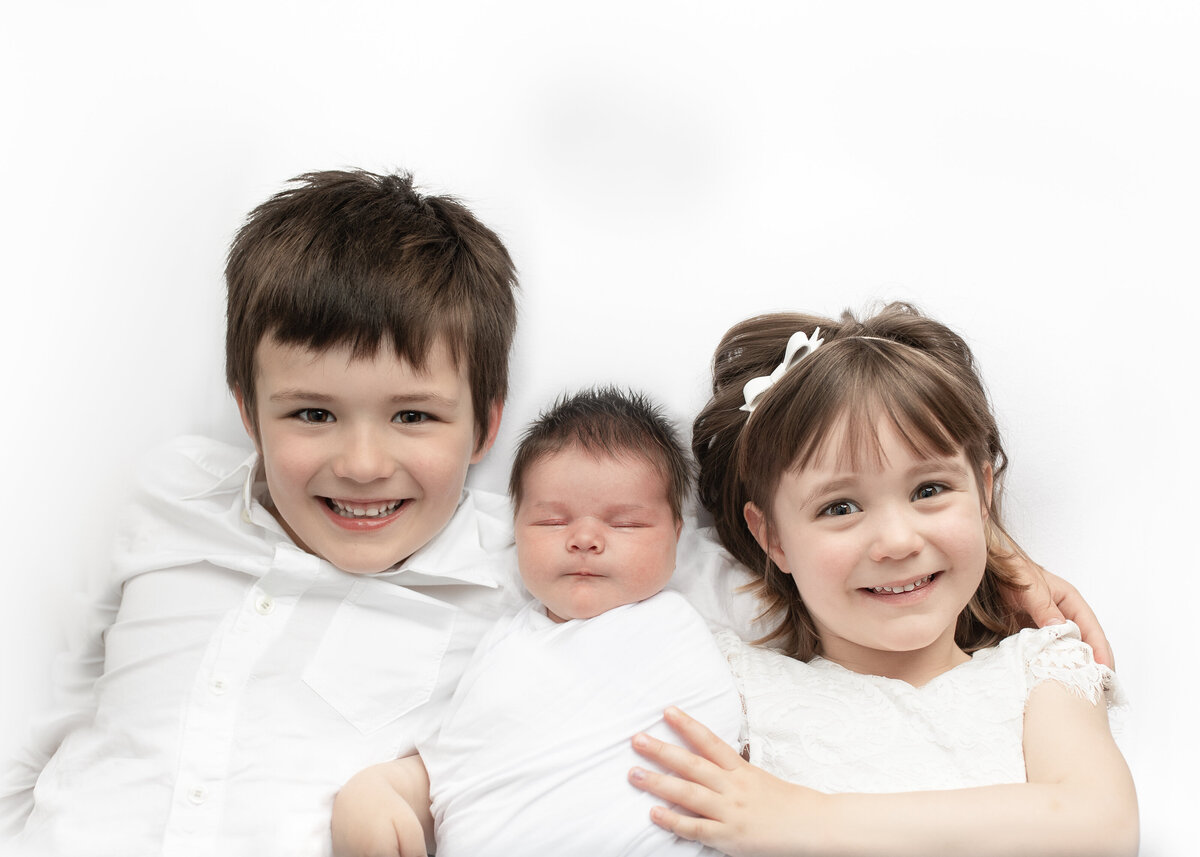 Newborn and sibling Photo  with Big brother and big siter smiling for the camera, aken during a Hobart Newborn Photography Session by Lauren Vanier Photography.