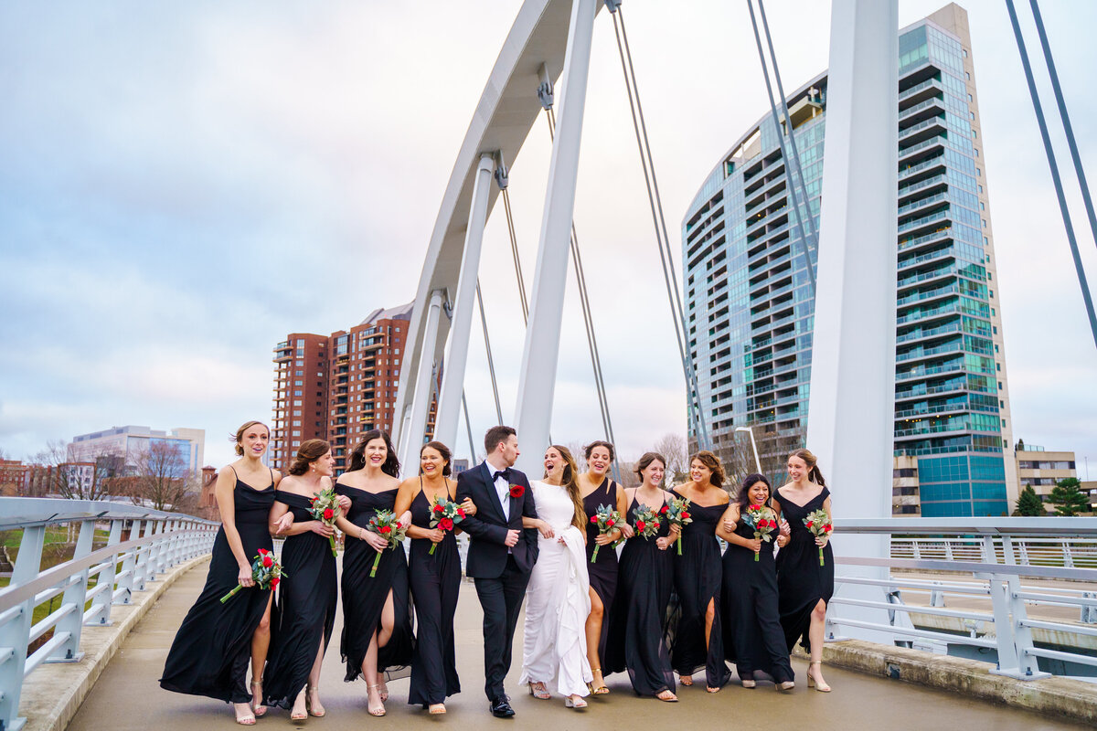 Bride and her squad laugh as they walk along a bridge across the Scioto River in Columbus, Ohio.
