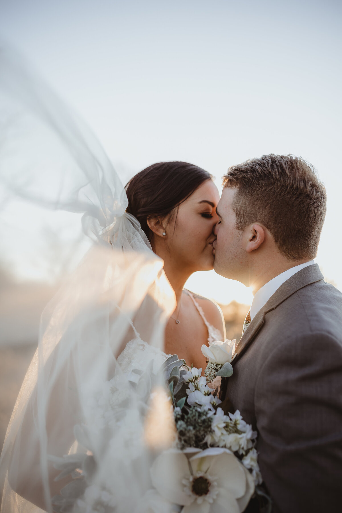 WEDDING DAY PRIVATE KISS NEWLEYWEDS WIND BLOWING VEIL SUNSET GOLDEN HOUR