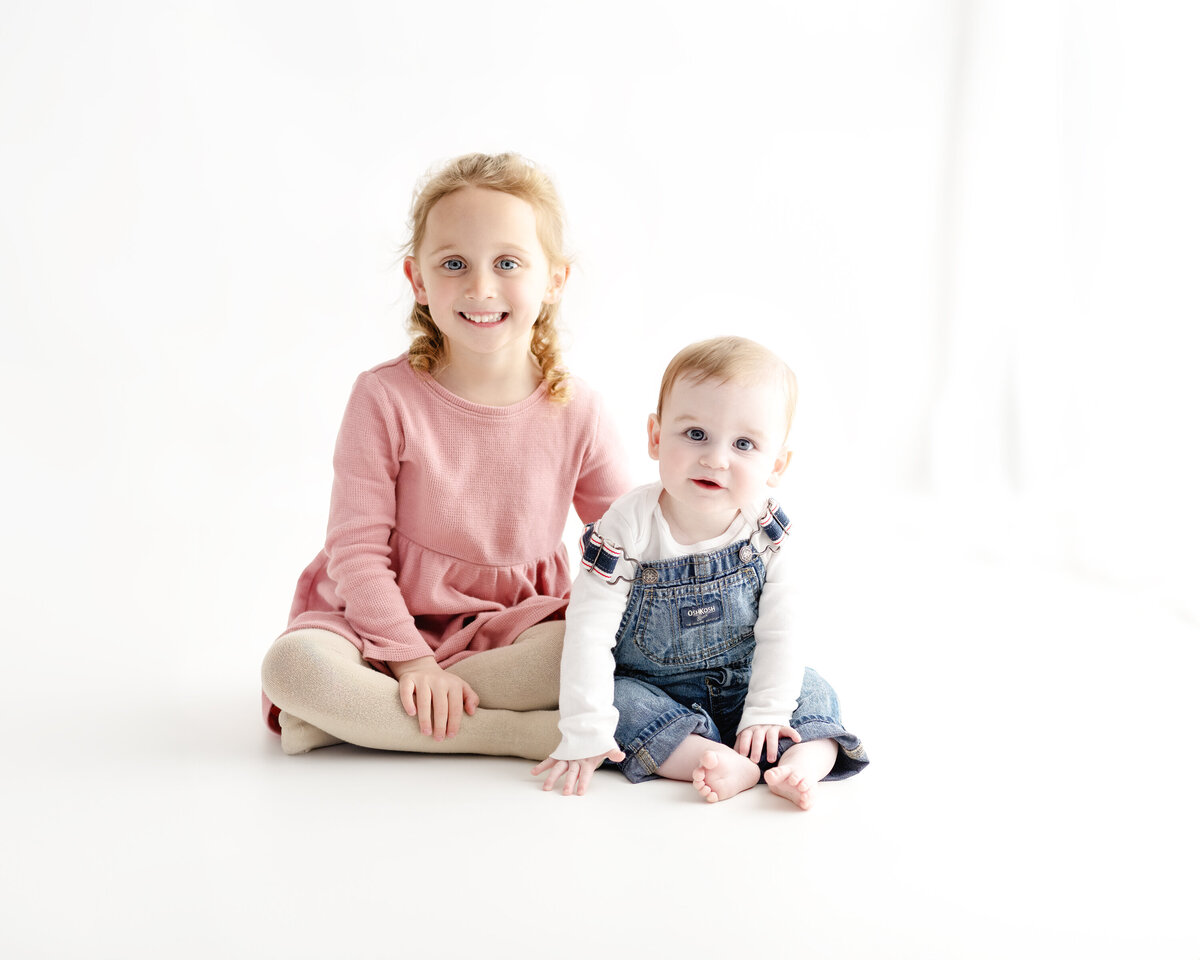 Sibling and baby portrait in a white studio setting—capturing the joy and warmth of family during a milestone session in Paris, Ontario.