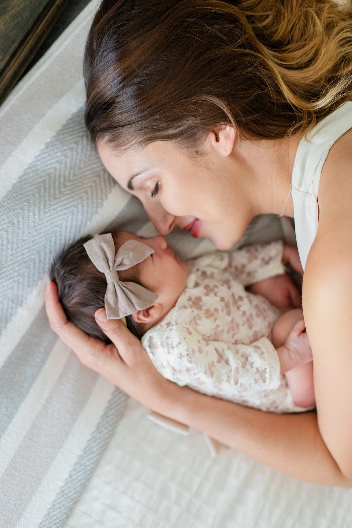 mom snuggles with newborn in bed