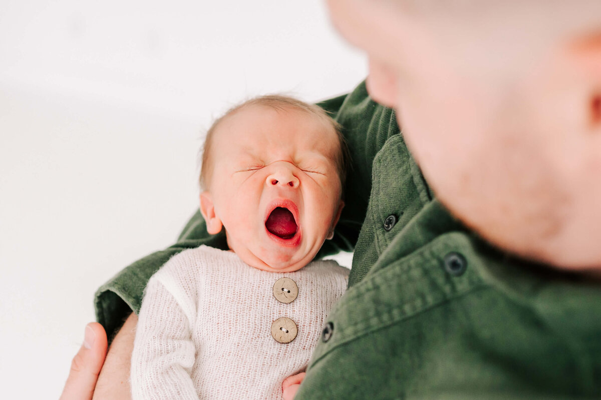 Springfield MO newborn photographer Jessica Kennedy of yawning newborn in fuzzy white sleeper