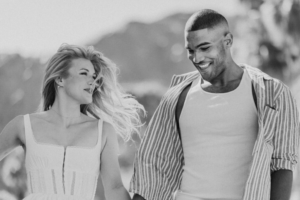 Black and white close-up of couple sharing a joyful moment, faces turned toward each other in soft connection.