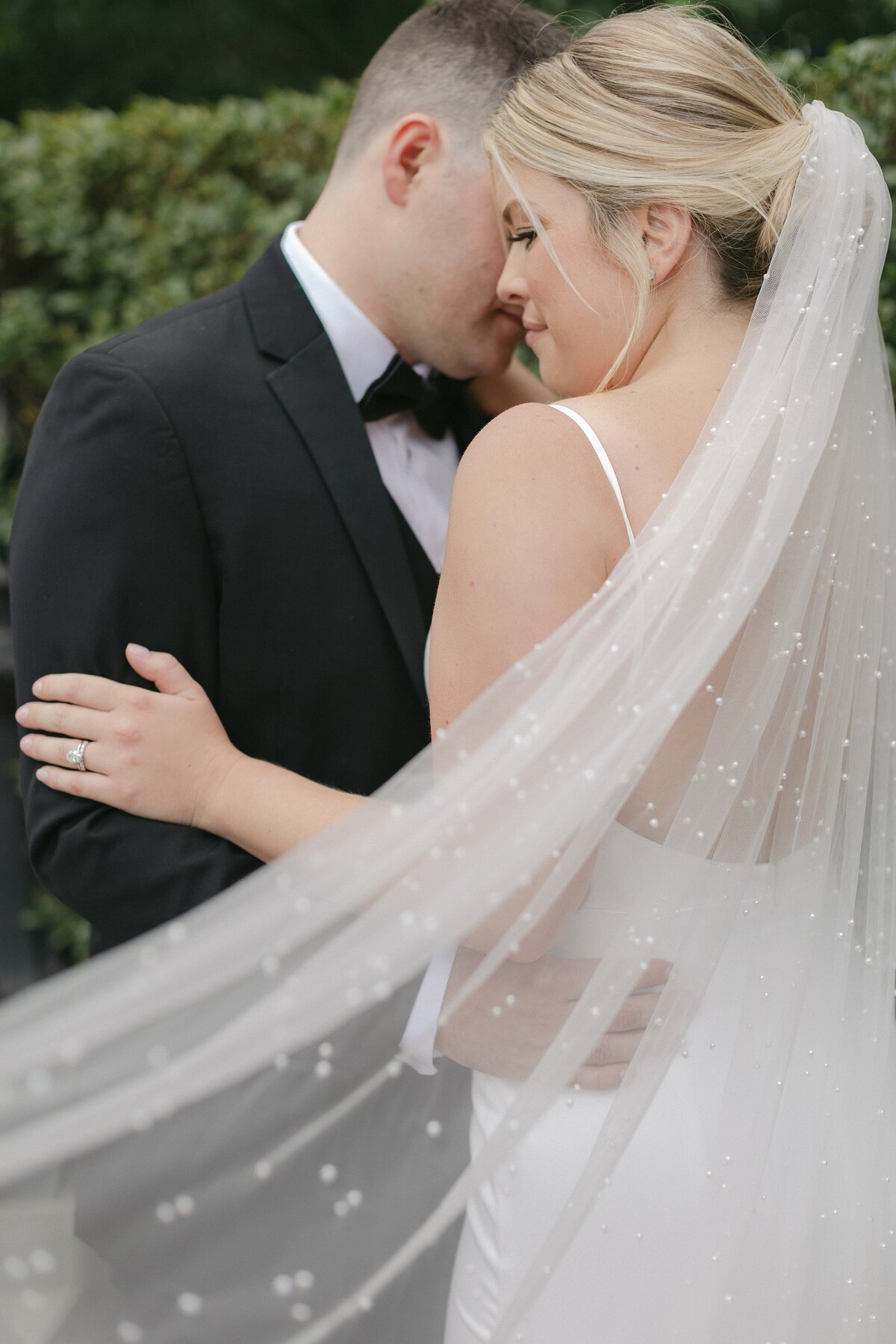 Bride and Groom embrace with veil in foreground.