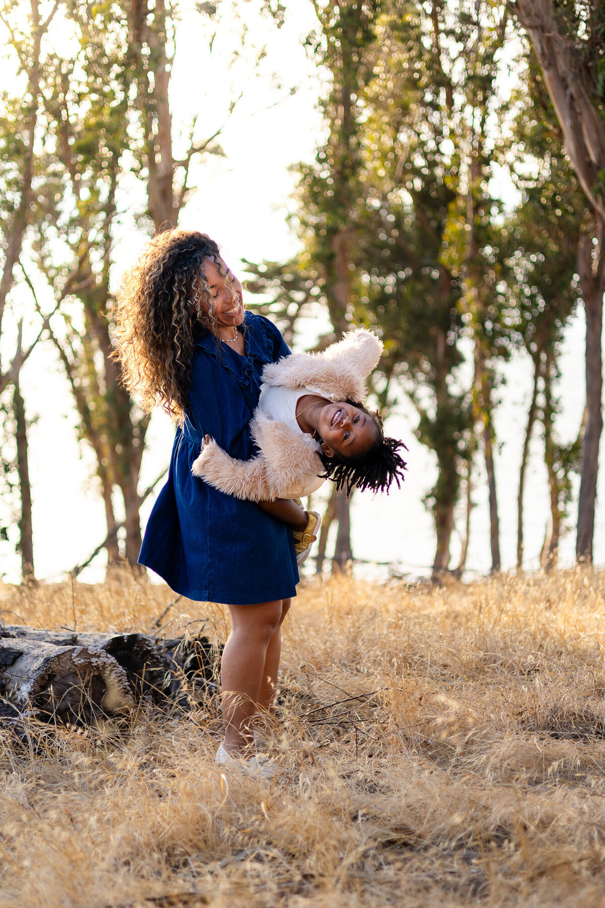Mother holding daughter upside down while smiling in golden field, Bay Area Family Portfolio – Ellobelle Photography