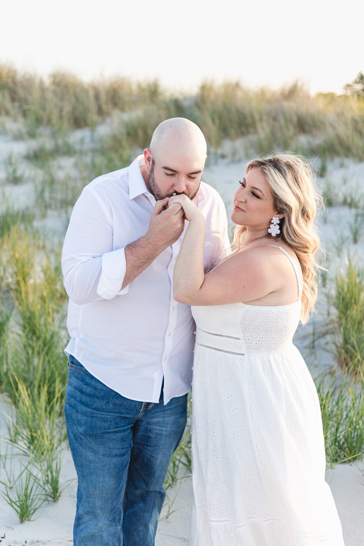Man kisses his fiancee's hand as she looks at him adoringly