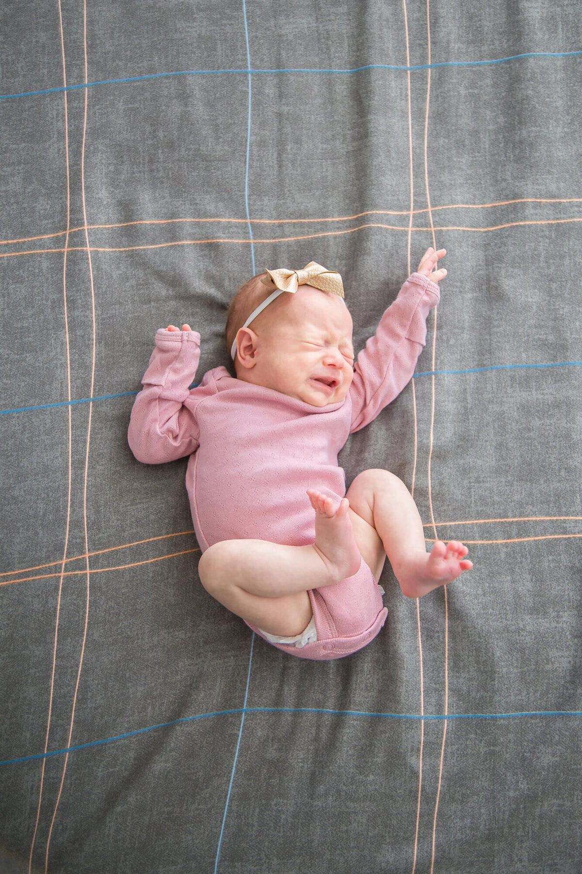 Newborn baby girl in pink onesie sneezing during newborn session with  Las Vegas newborn photography professional