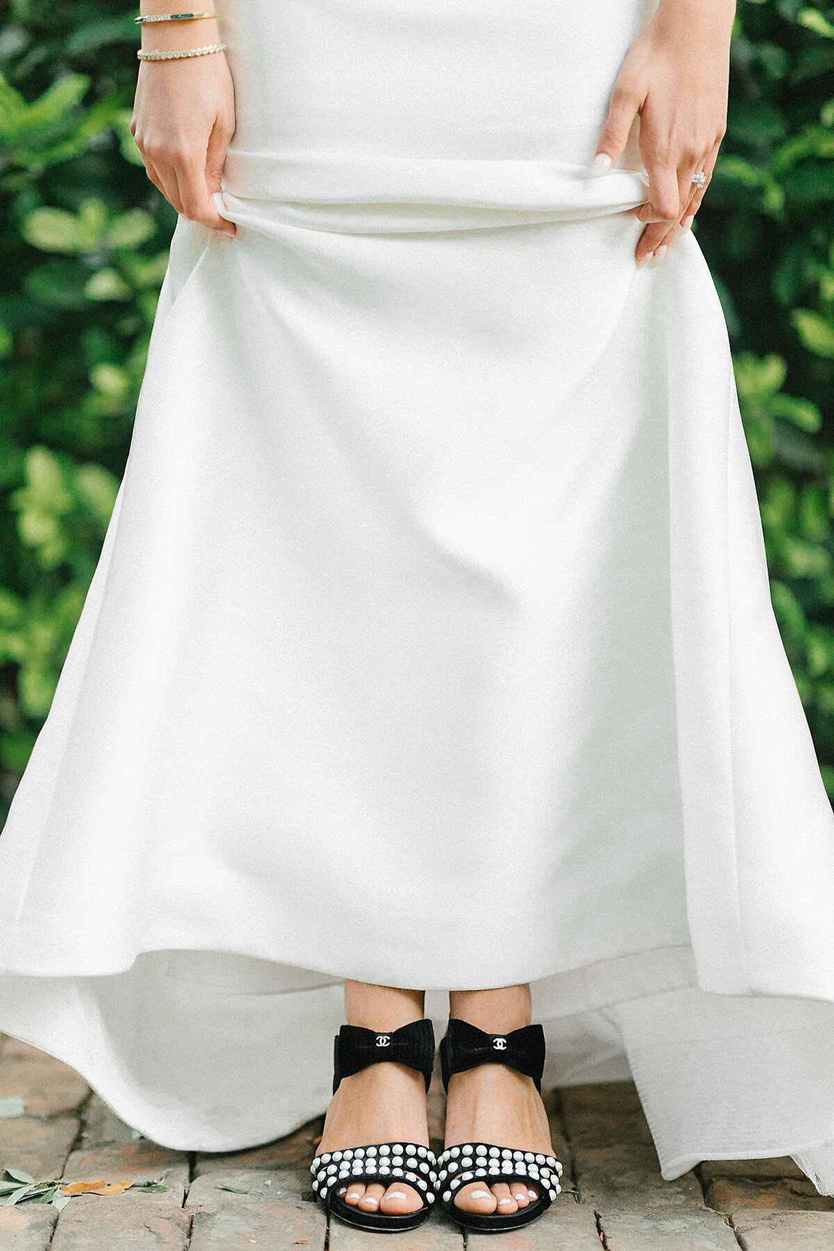 bride lifting wedding dress to reveal black pearl Chanel bow shoes