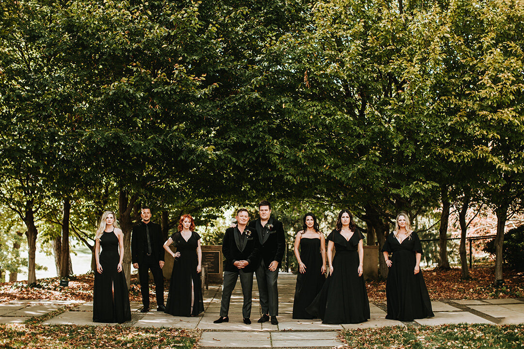 Wedding party wearing all black outdoors surrounded by large trees