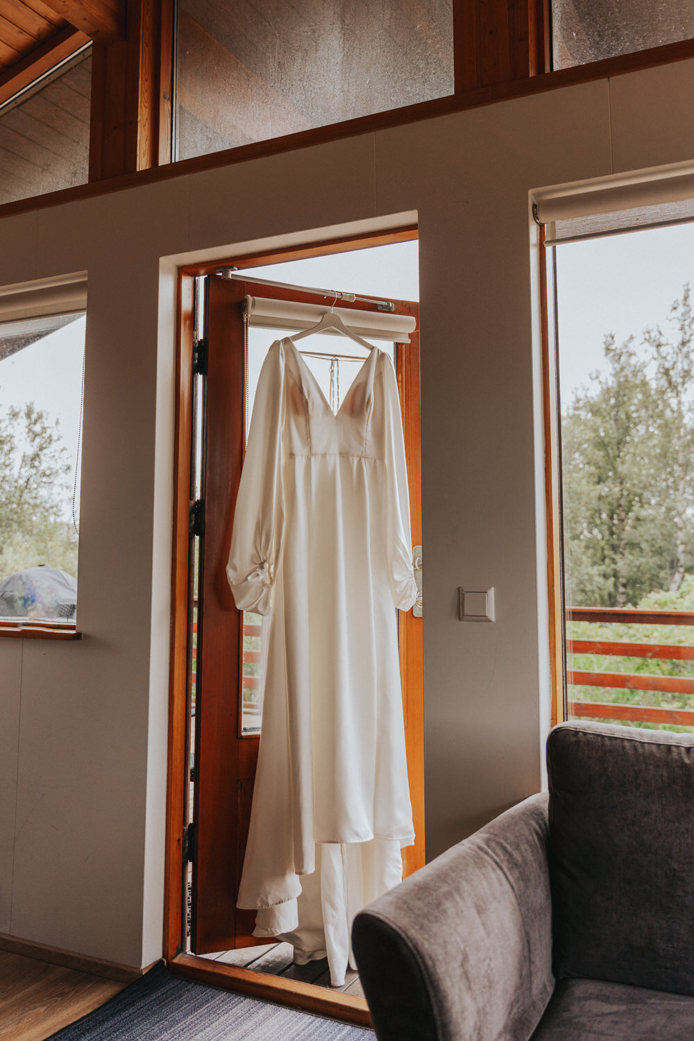 White wedding gown hands from a wooden door in an Iceland cottage 