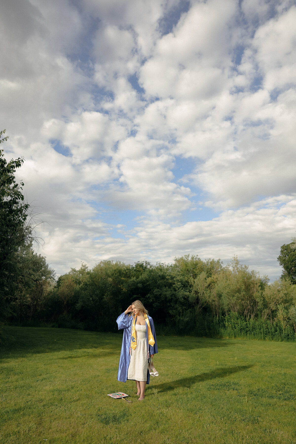 Golden Hour Senior Portrait of Girl Twirling in White Dress with Sun Flaring Through Trees
