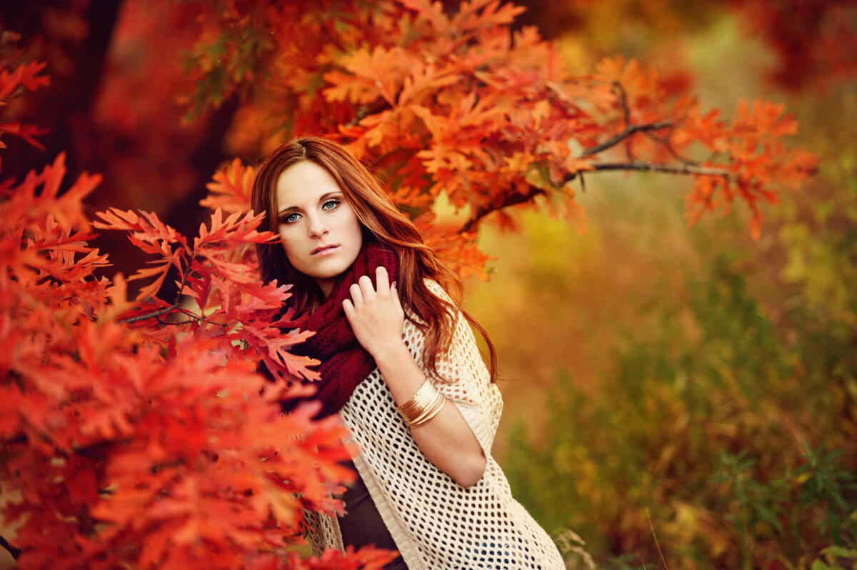 senior picture of girl in white sweater with bright orange leaves in fall
