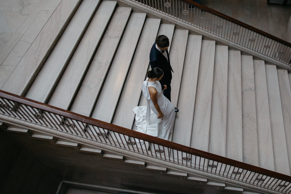 Overhead photo of bride and groom walking down marble stairs
