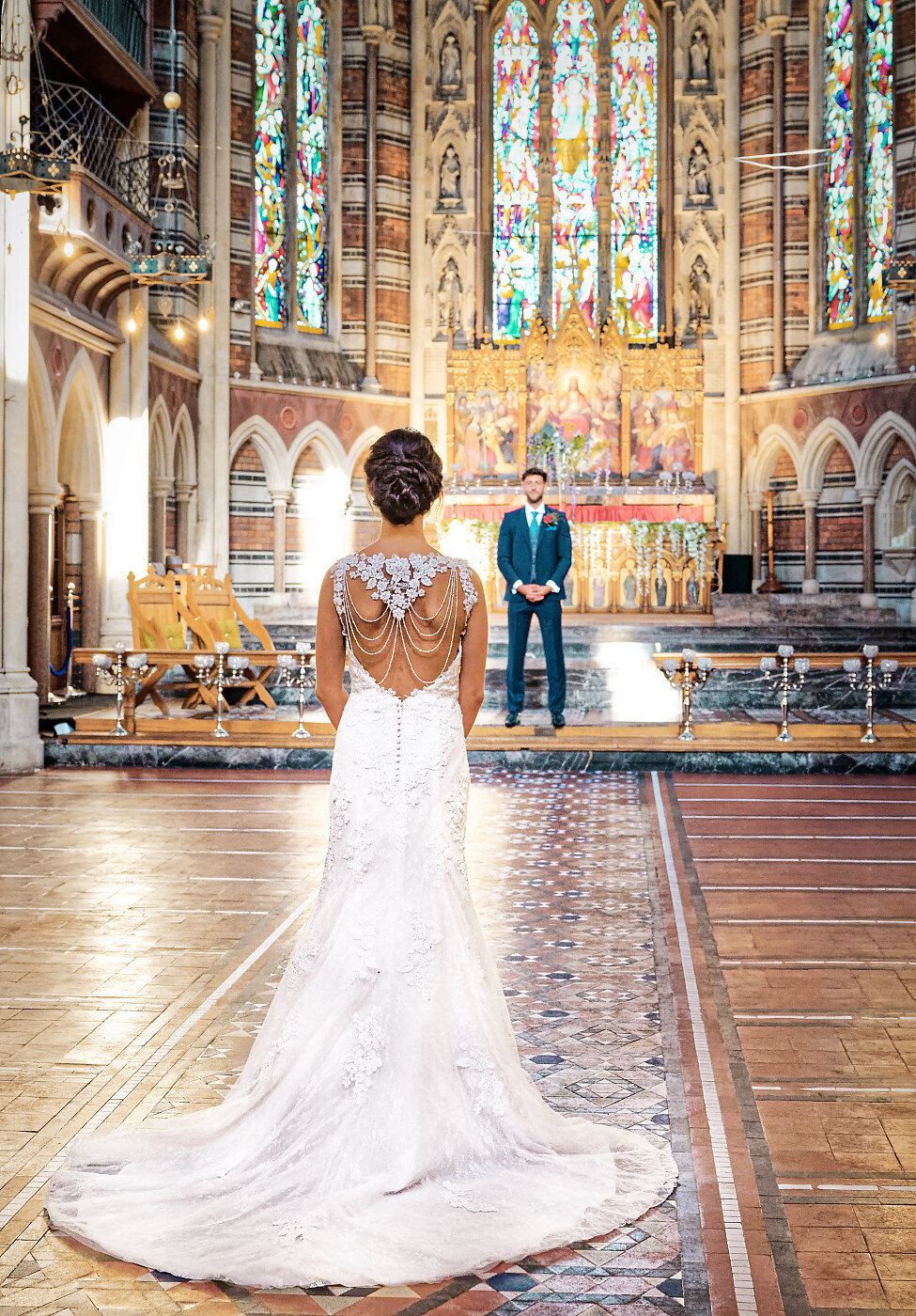 Bride and groom looking at each other surronded by stained glass windows in a chapel