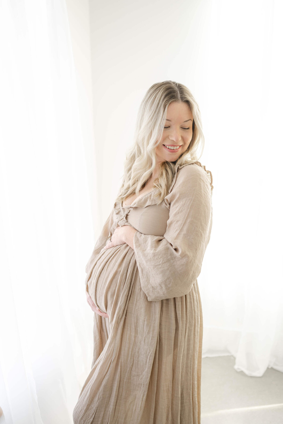 mom to be holding her bump looking towards the Wheeler Ferris Wheel