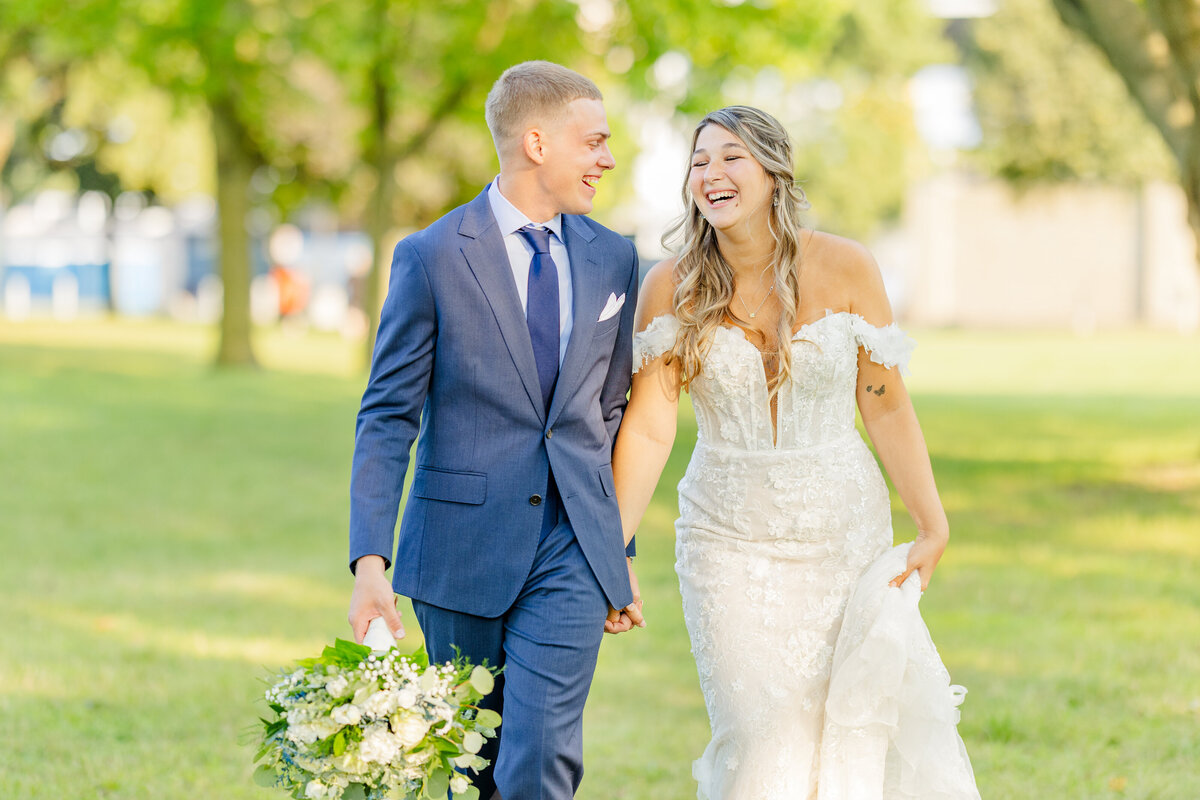 groom-and-bride-laughing-while-walking-holding-hands-freedom-hill
