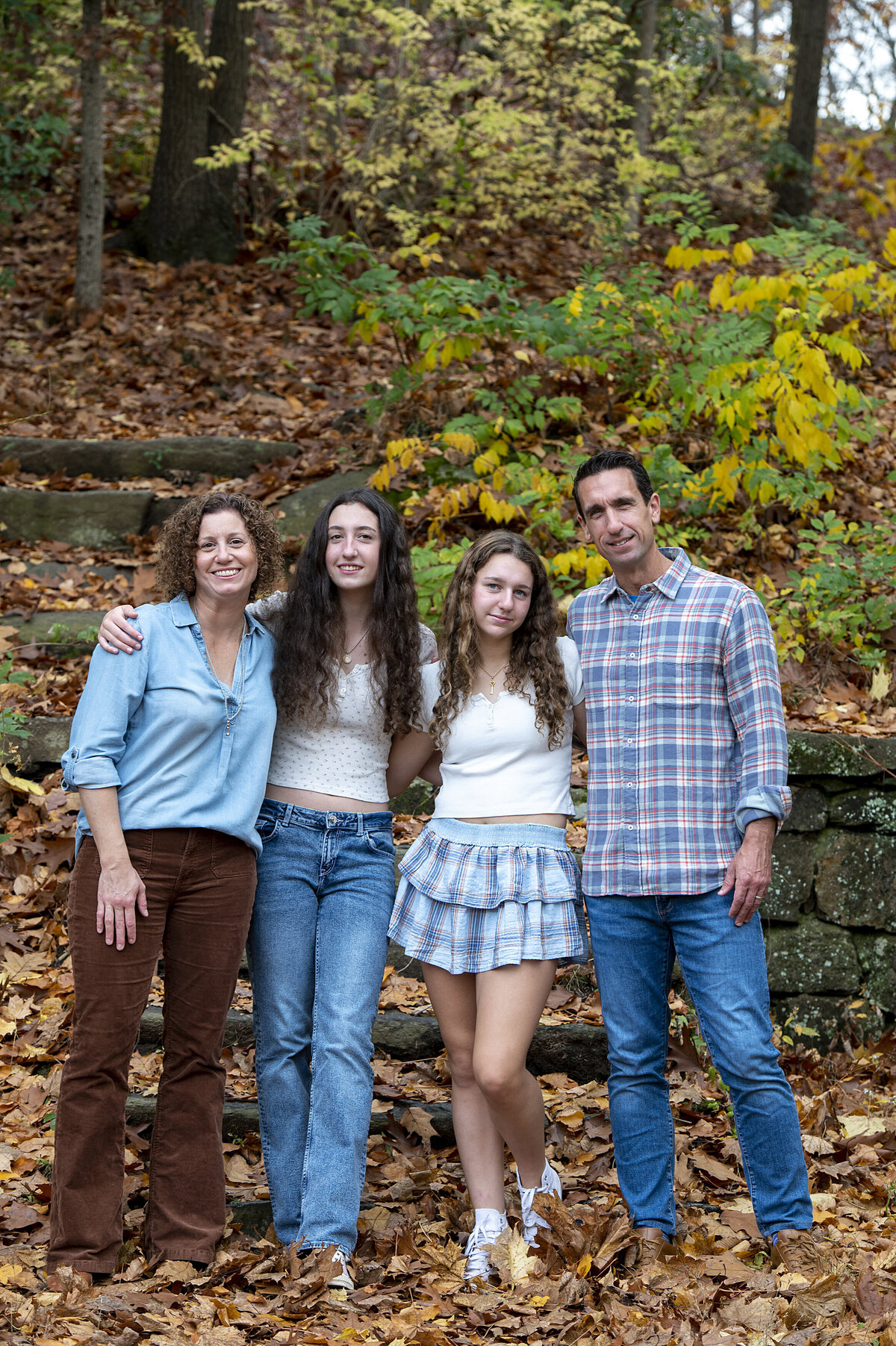 A family of four standing in a line with their arms around each other 