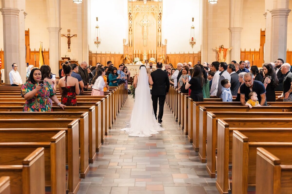 Bride walking down aisle surrounded by guests