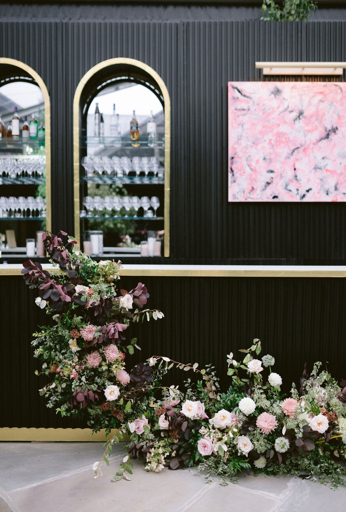 Moody welcome party for fall wedding weekend. Tented reception for outdoor wedding reception at Blackberry Farm. Moody floral design with colors of deep magenta, mauve, eggplant, blush, and natural greens. Rich tones with roses, mums, and smokebush foliage. Romantic candle light and large trees create a magical setting for a welcome party. Destination wedding at Blackberry Farm. Design by Rosemary & Finch Floral Design in Nashville, TN.