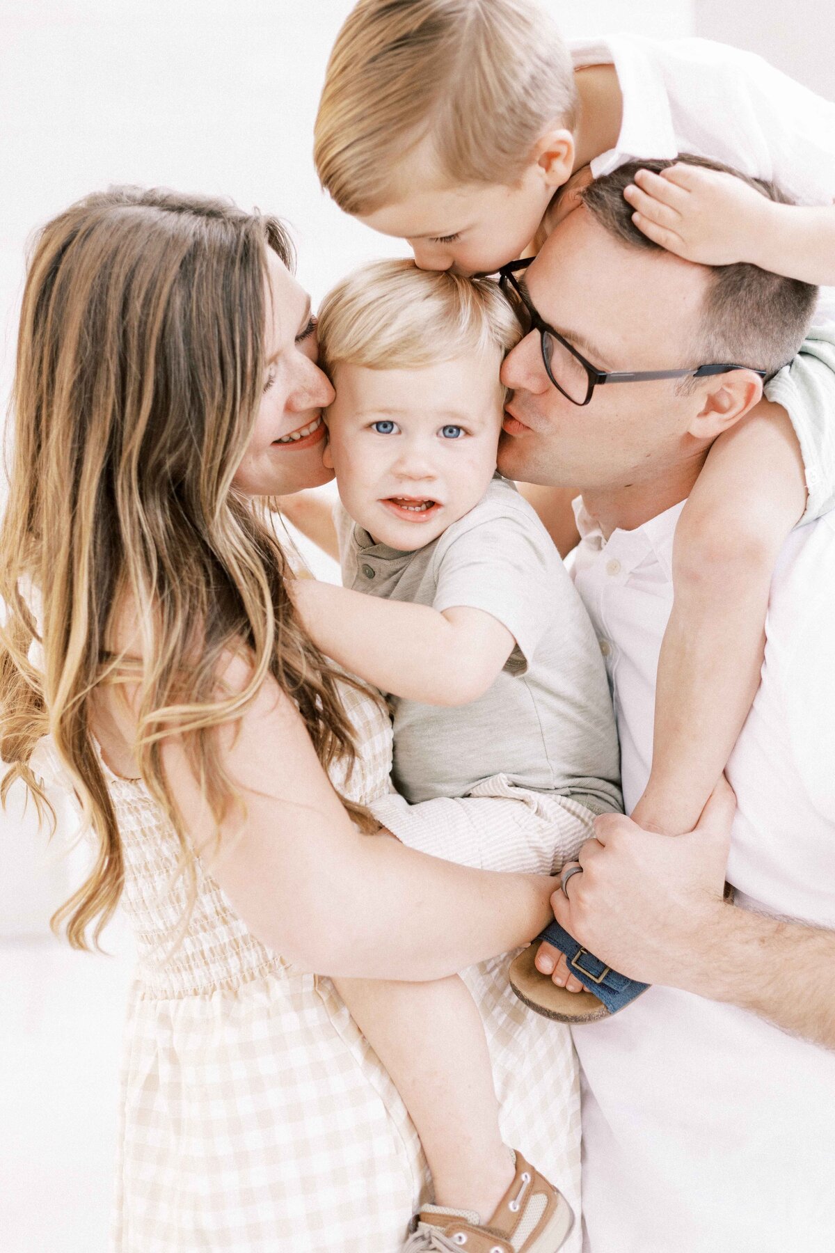 family kissing child during maternity photos in peoria, illinois