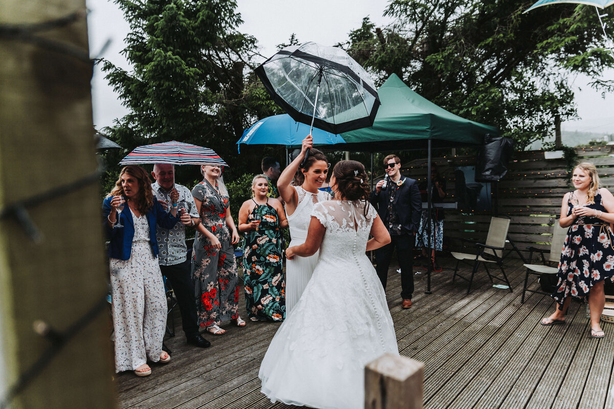 two brides dancing in the rain