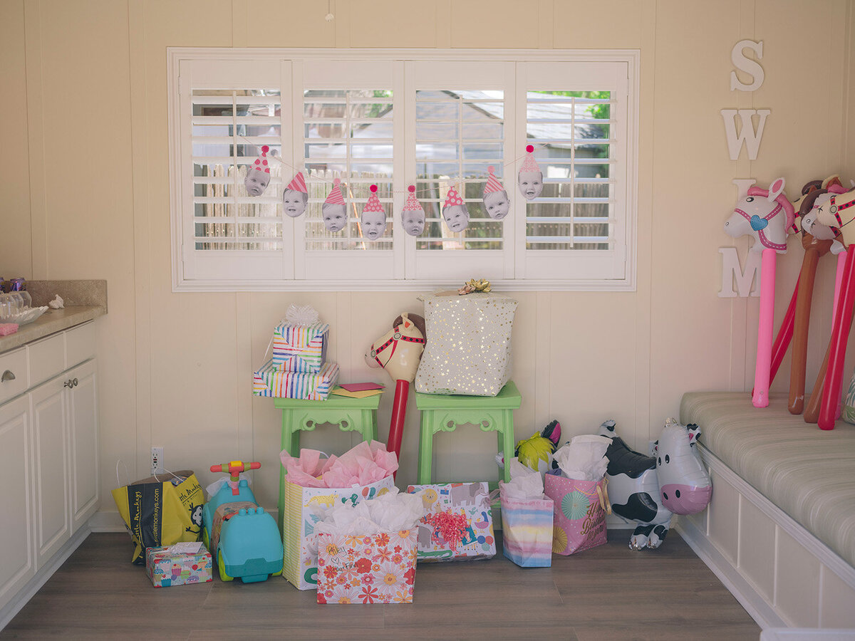 Birthday presents and colorful party decor inside a pool house at a first birthday party in the San Francisco Bay Area.