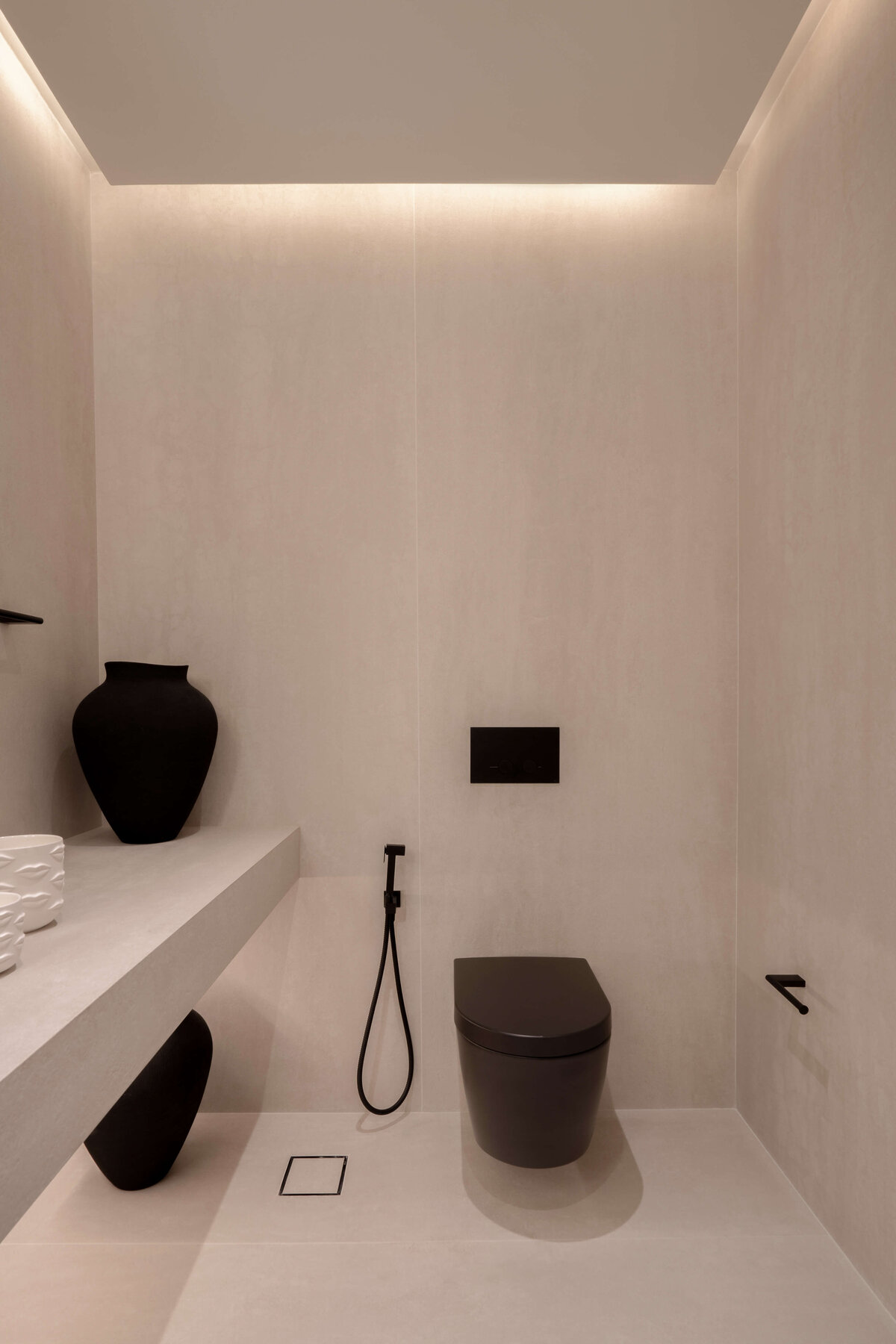 Modern bathroom featuring a light, airy aesthetic contrasted by a dramatic sleek black toilet and black vases.