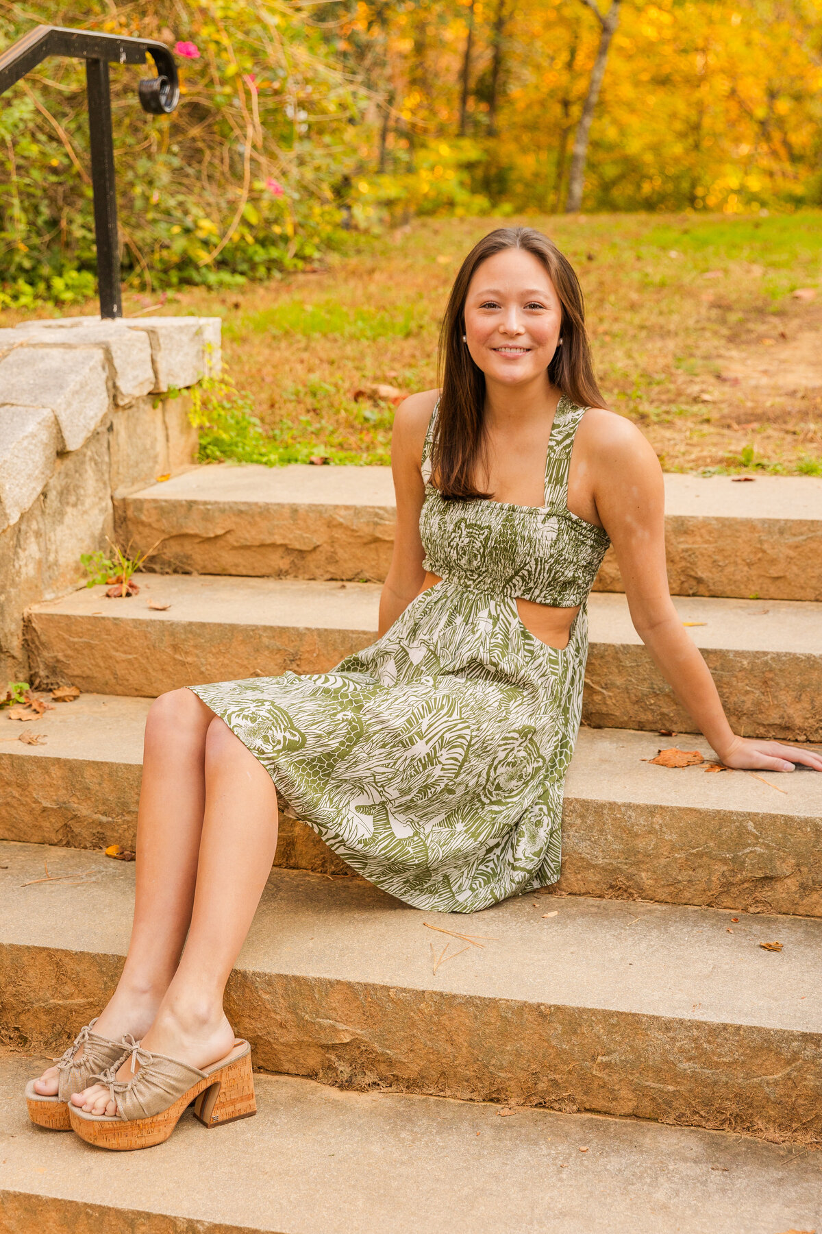 wide shot of a senior girl sitting on pAtlanta park steps looking at the camera during portraits session