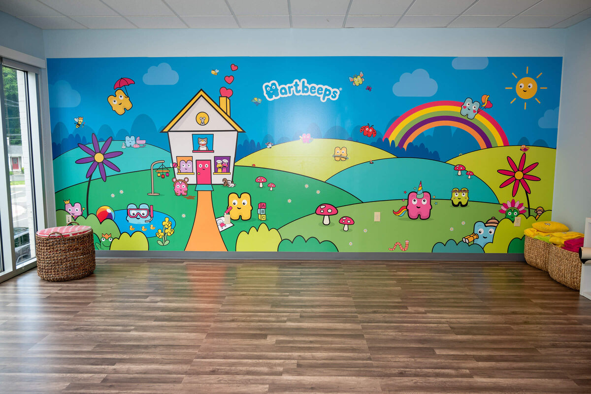 An empty room, showing off a colorful mural on the wall for Hartbeeps: a sensory music class for babies and toddlers, in their brand new space in downtown Westport, CT.
