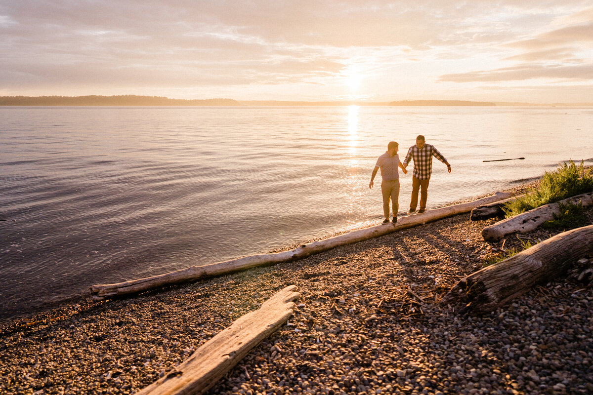 Couple balancing on a log along Puget Sound, one of the top places for engagement and wedding pictures in Seattle