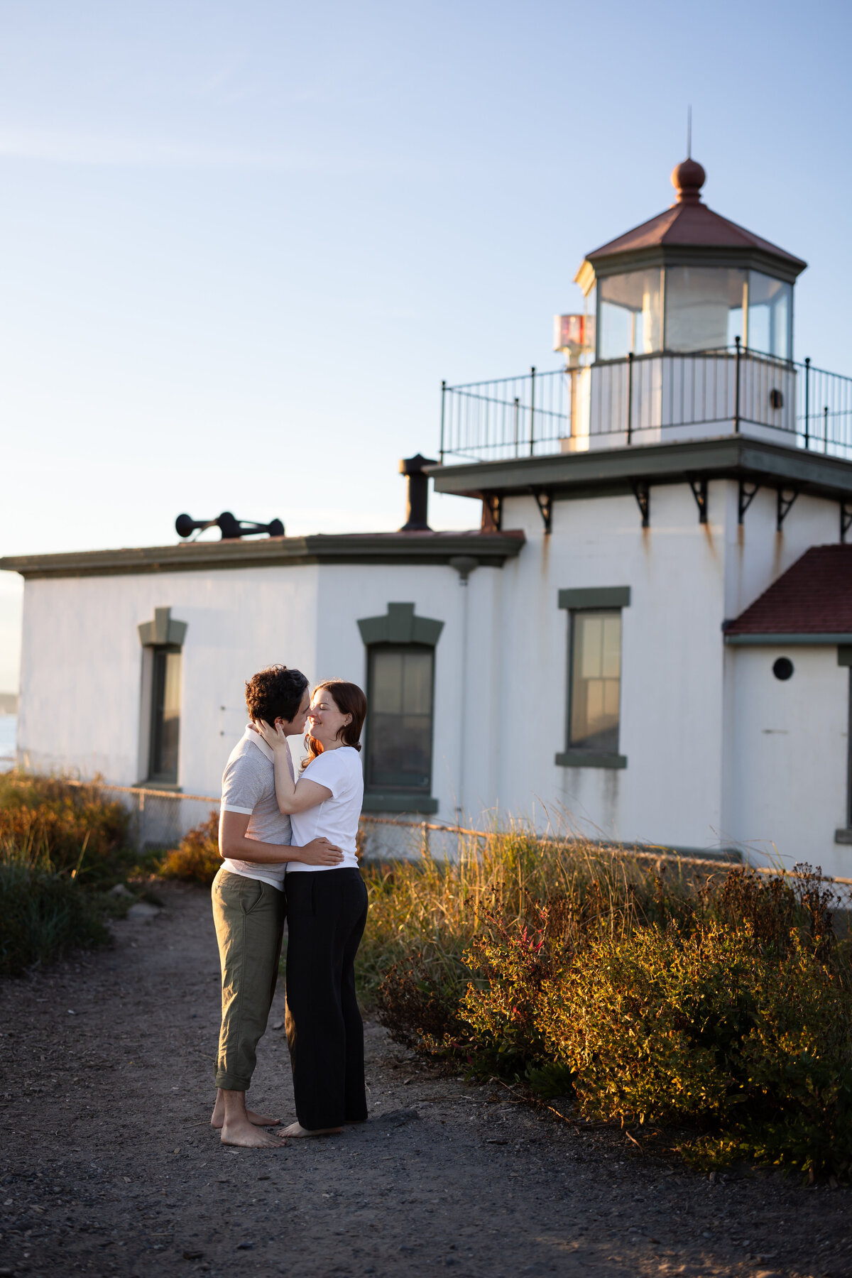 couples photo session in front of a light house on the beach in seattle washington