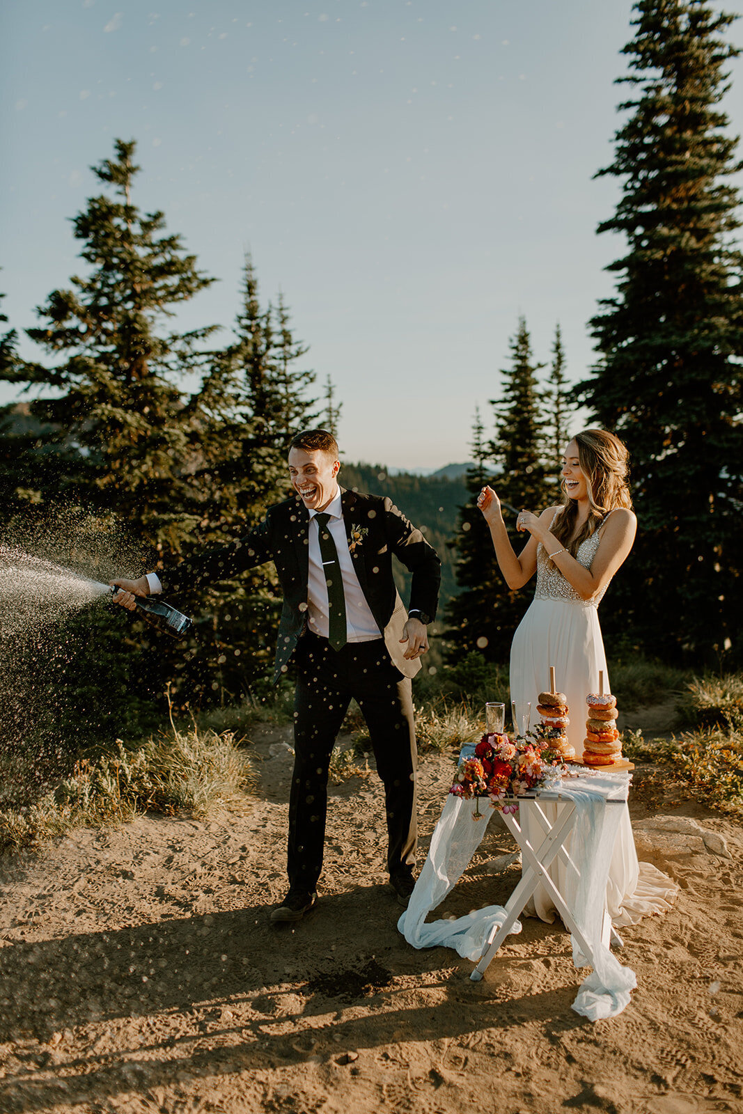 Bride & groom celebrating with champagne & doughnuts on trail in Mount Rainier National Park after their elopement ceremony!