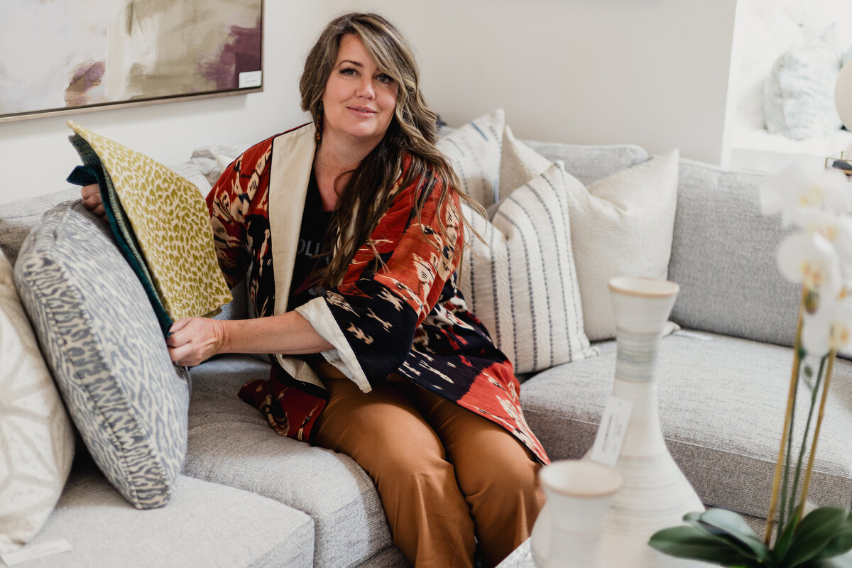 Interior Designer on showroom  couch holding up textiles against fabric
