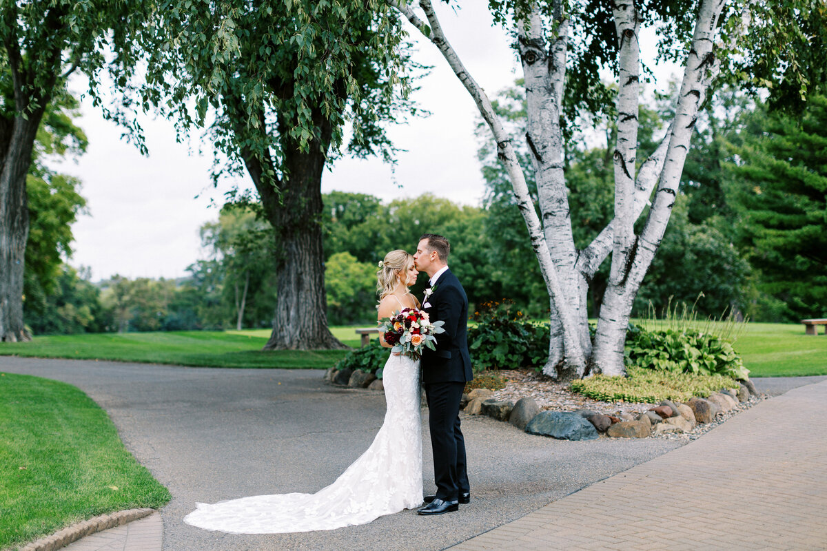 groom kissing bride's forehead  at Minneapolis Golf Club